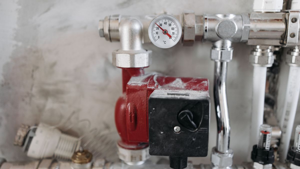 Bomba hidráulica vermelha com manômetro e controlador automático, instalada em tubulação metálica de sistema de pressurização